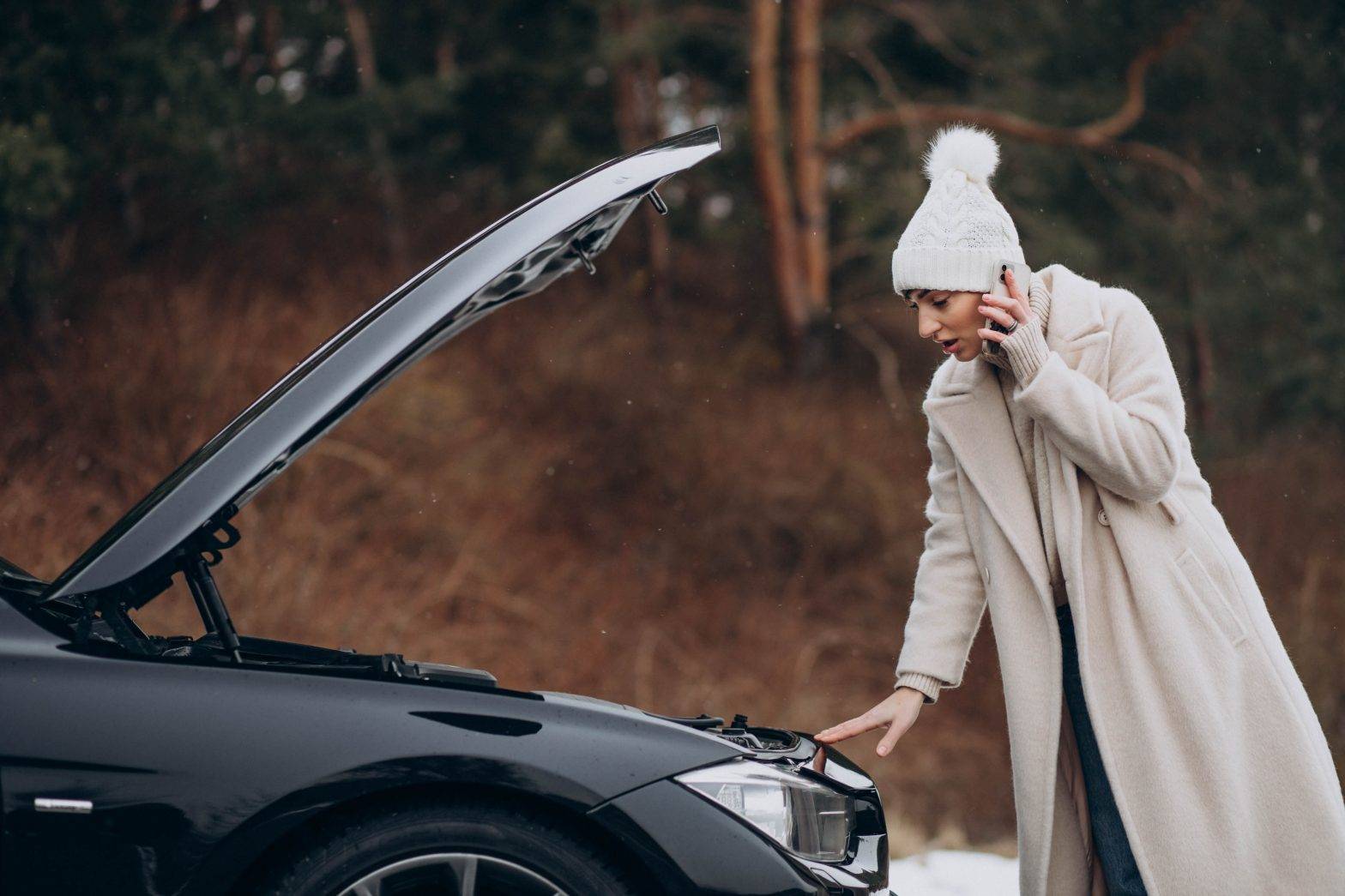 Young woman calling on the phone after her car brokedown in winter season - Cuidados com o seu carro no inverno